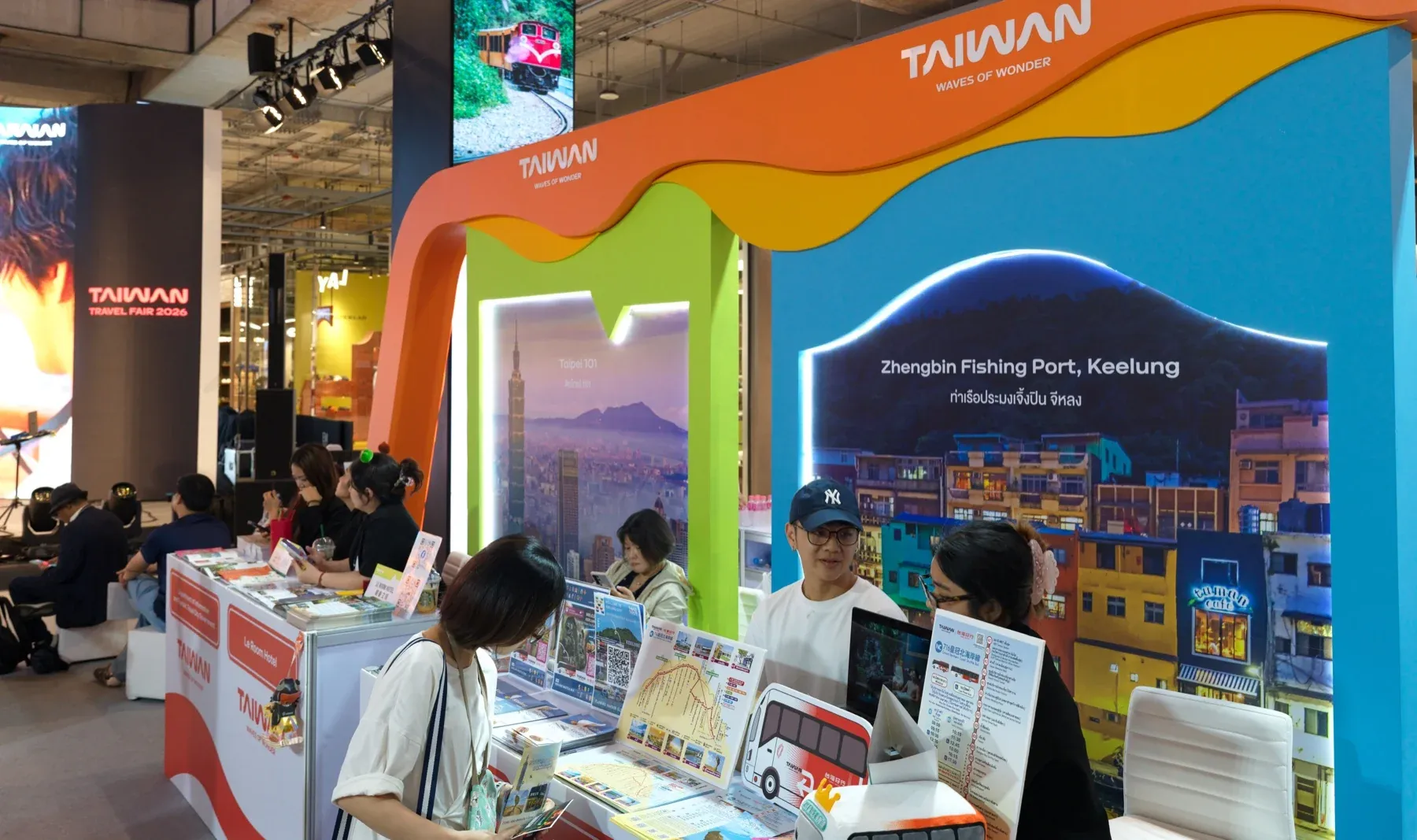 以基隆正滨渔港和台北101为背景的旅游展台,参观者与工作人员交流