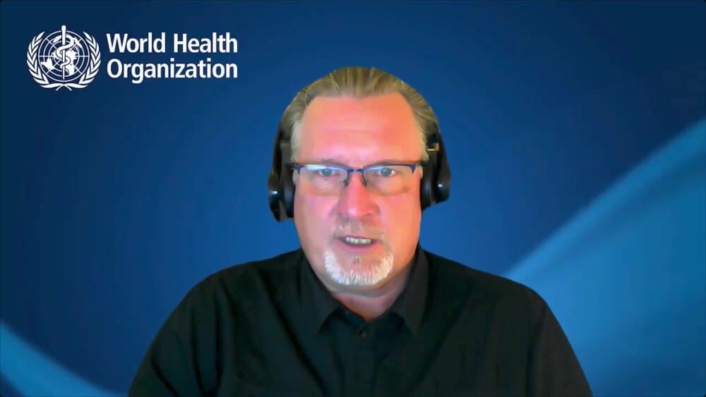 WHO spokesperson Christian Lindmeier speaking with a headset against a WHO-branded background